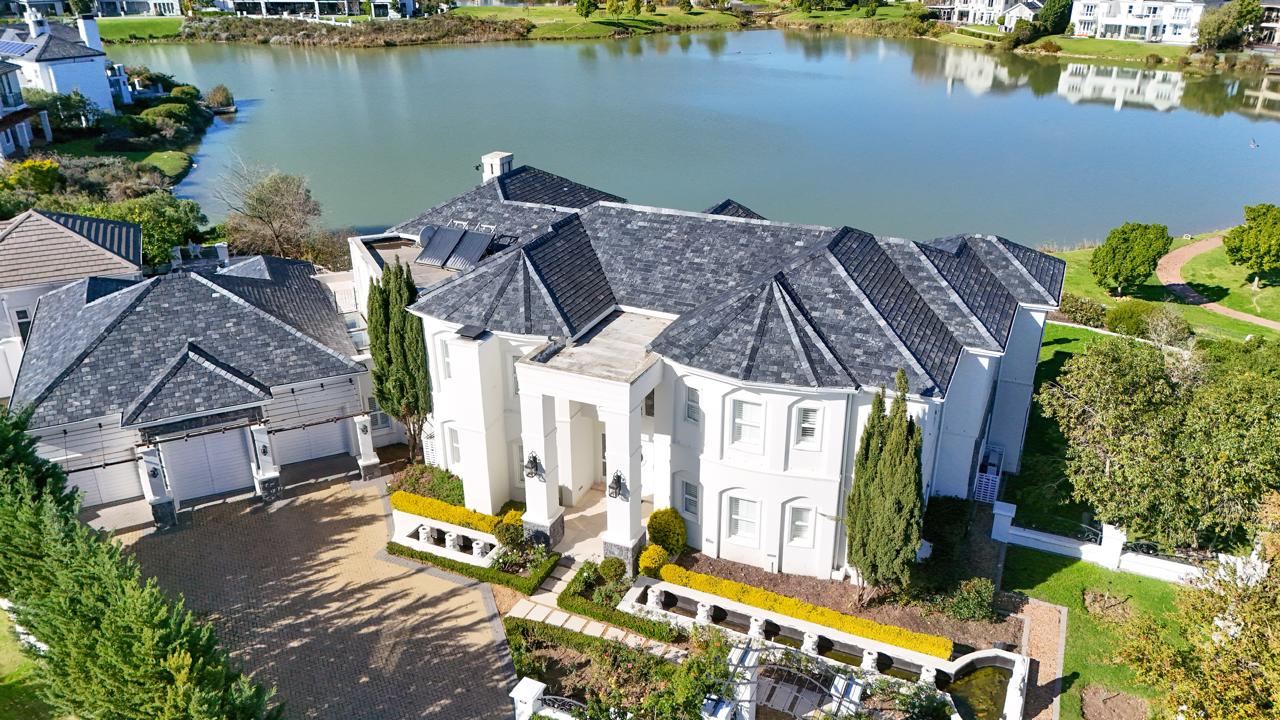 Aerial view of a grand lakeside estate home in the Cape Winelands